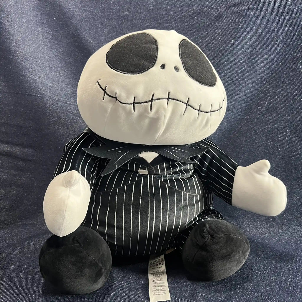 A plush toy of Jack Skellington from The Nightmare Before Christmas, wearing his black and white pinstripe suit, sitting against a blue textured fabric background.