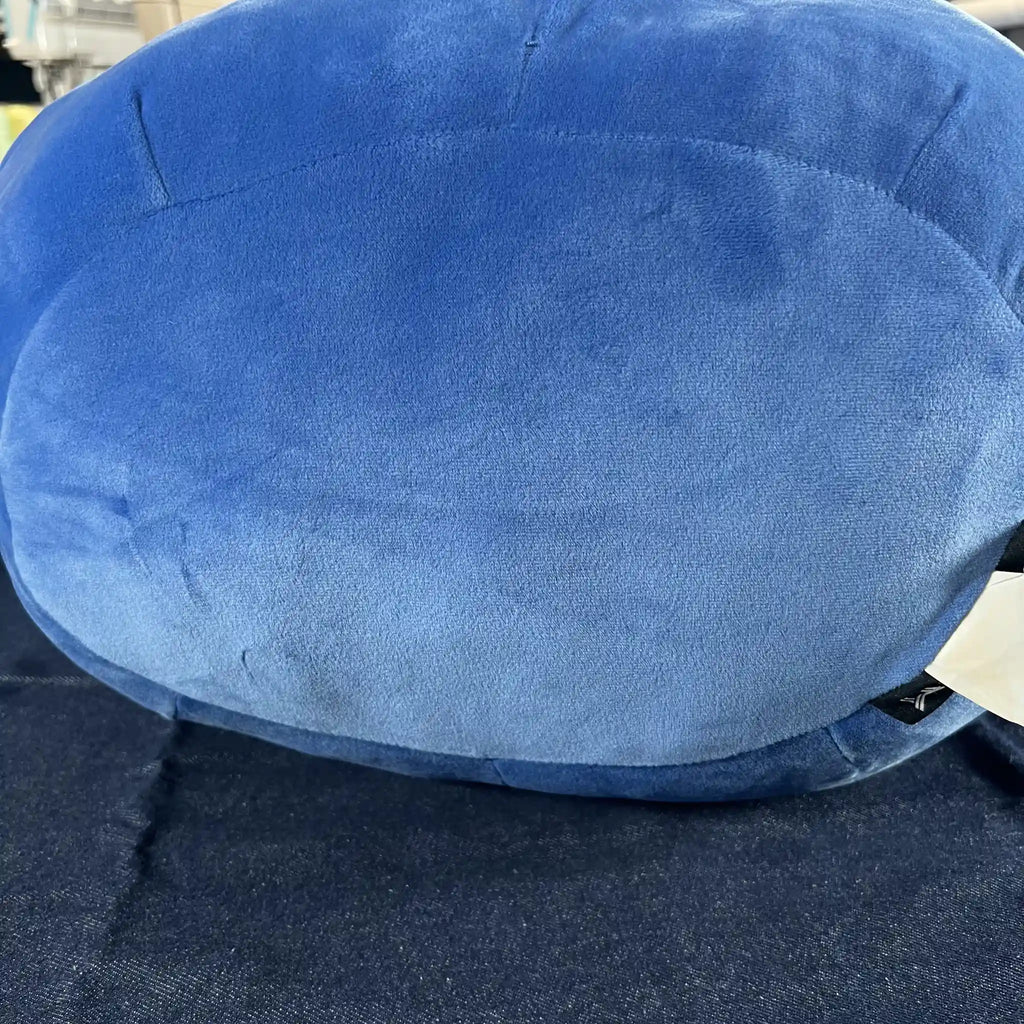 A close-up of a blue plush, showing the soft fabric texture and stitched seams, resting on a dark blue surface.